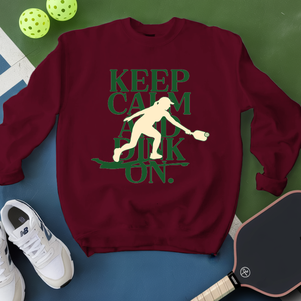 Maroon sweatshirt with 'Keep Calm and Dunk On' graphic on a green and blue background with pickleball equipment.