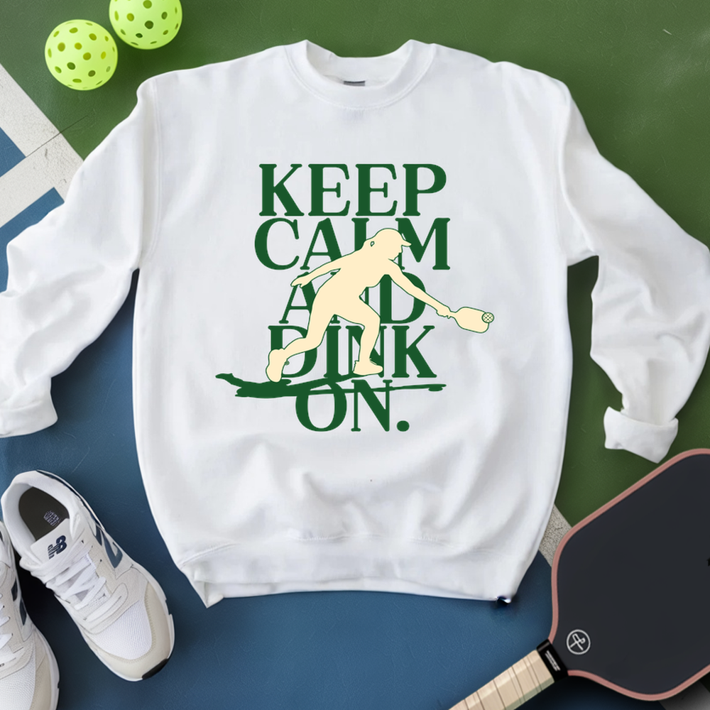 White sweatshirt with green text and pickleball graphic on a green and blue background