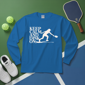 Blue long-sleeve shirt with 'Keep Calm and Dink On' graphic on a green and blue background with pickleball equipment.