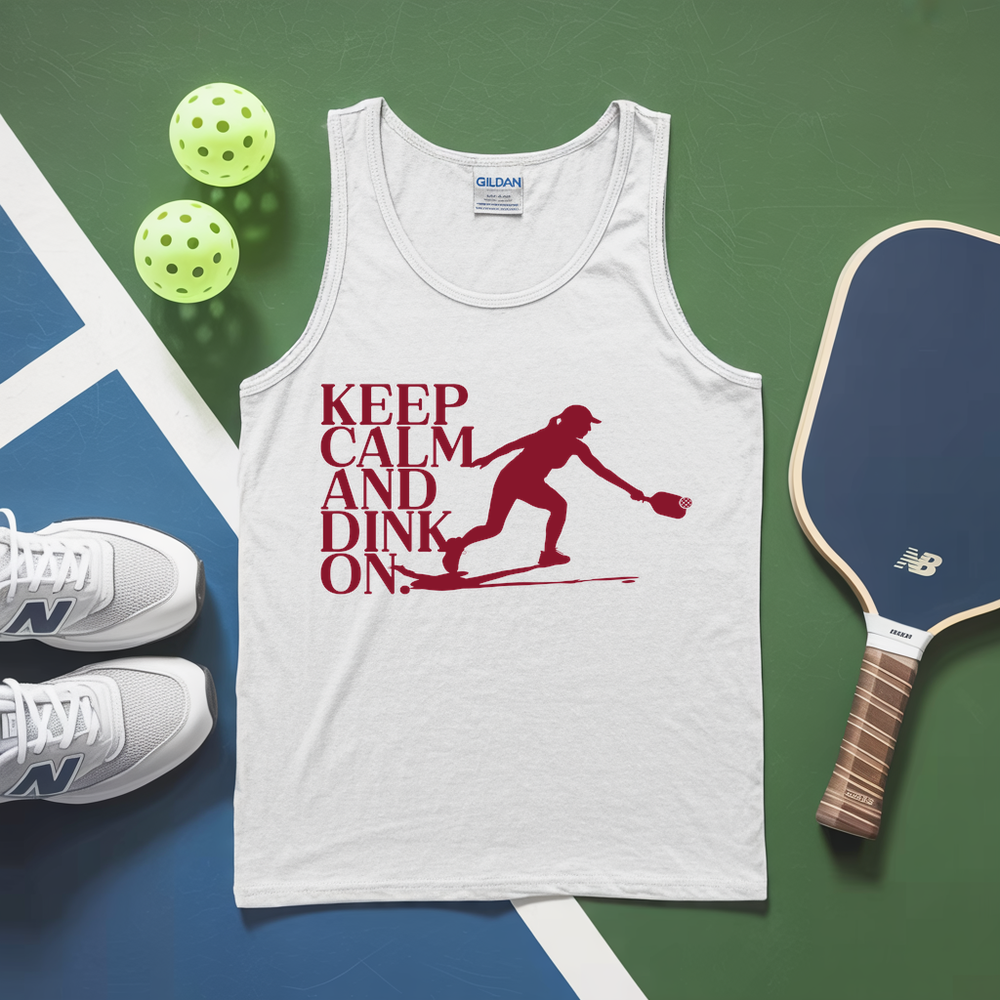 White tank top with red graphic and text, white sneakers, pickleball paddles, and balls on a green and blue surface.