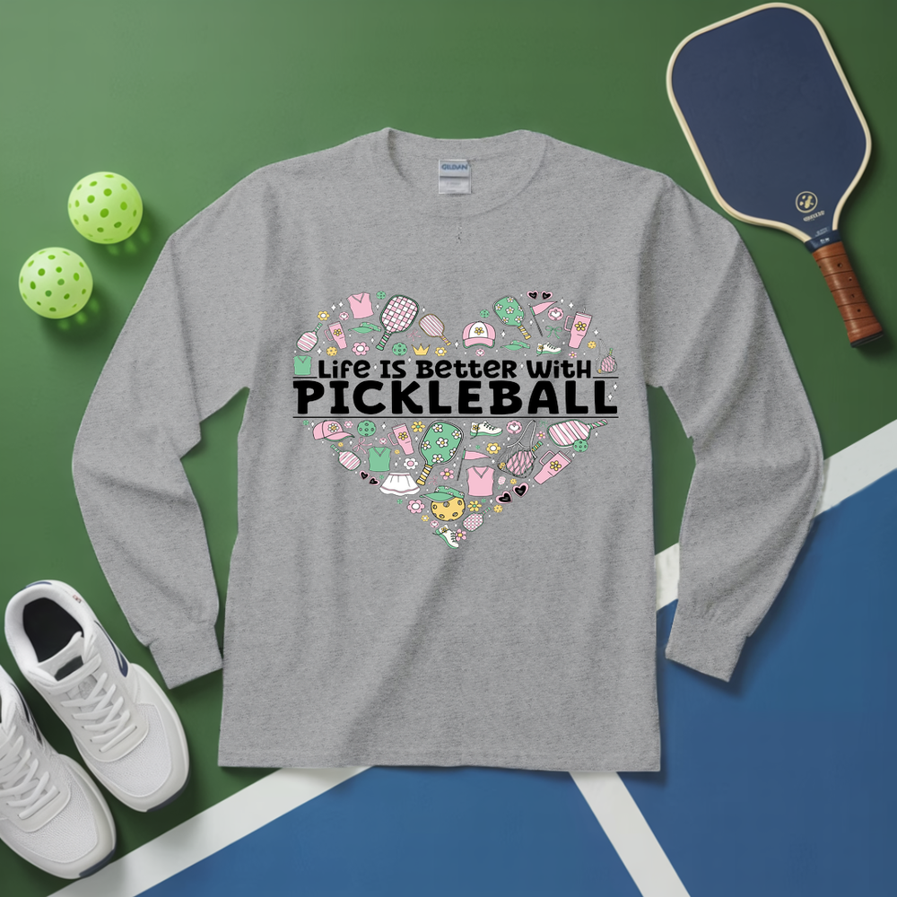 Gray long-sleeve shirt with pickleball-themed design on a green and blue surface with pickleball equipment.