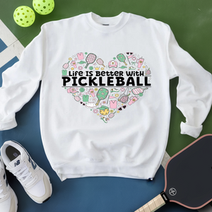 White sweatshirt with pickleball-themed design and text on a green and blue surface.