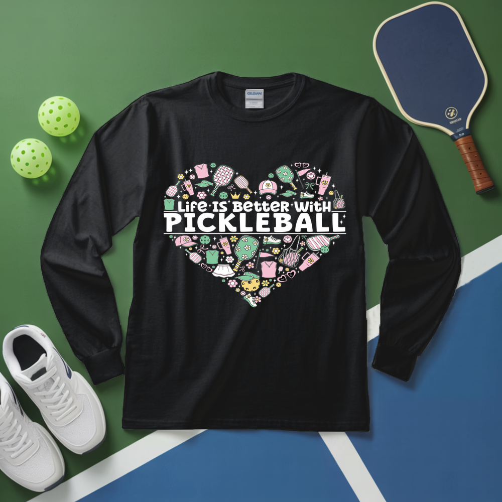 Black long-sleeve shirt with pickleball-themed design on a green and blue surface with pickleball equipment.