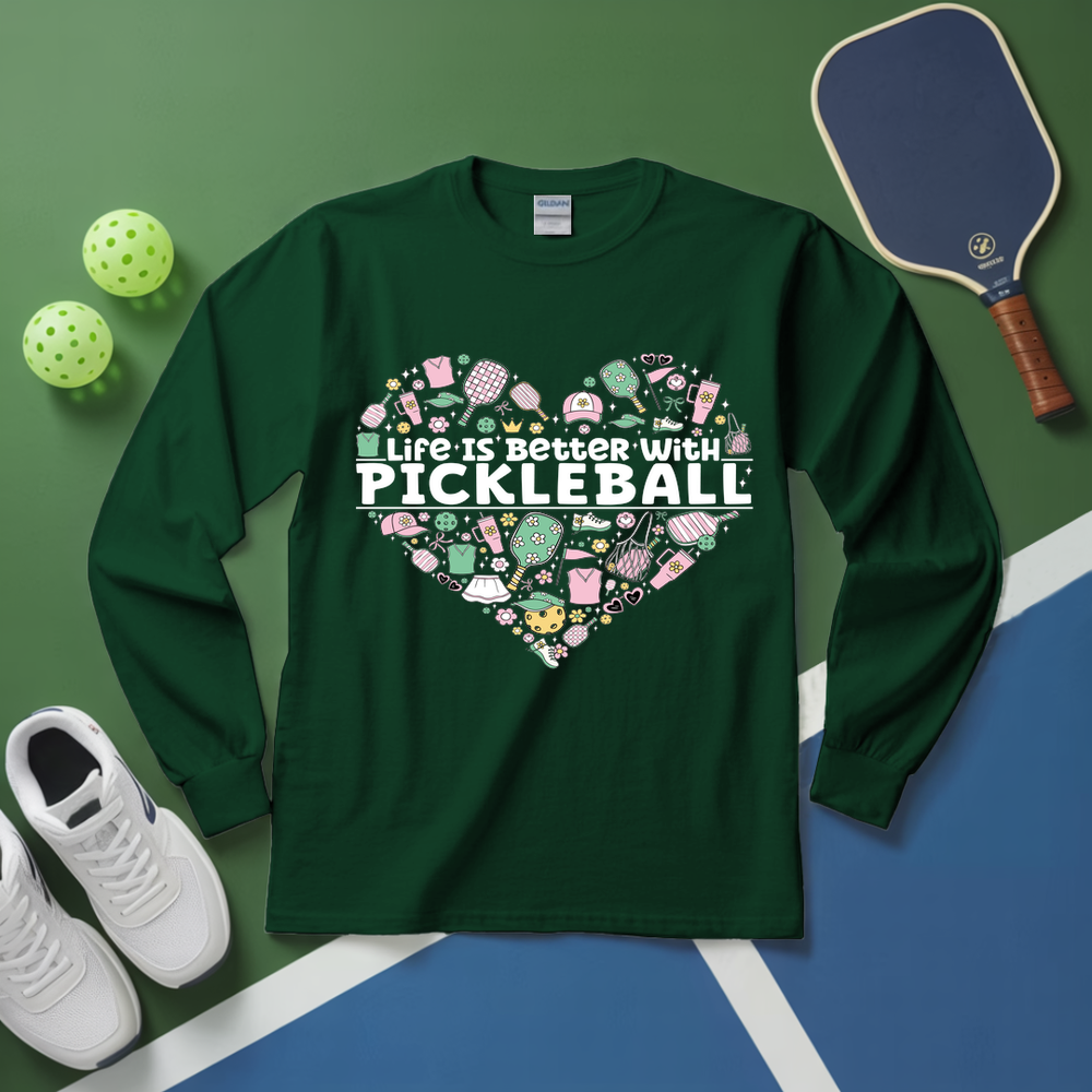 Green long-sleeve shirt with pickleball-themed design on a green and blue surface with pickleball equipment.