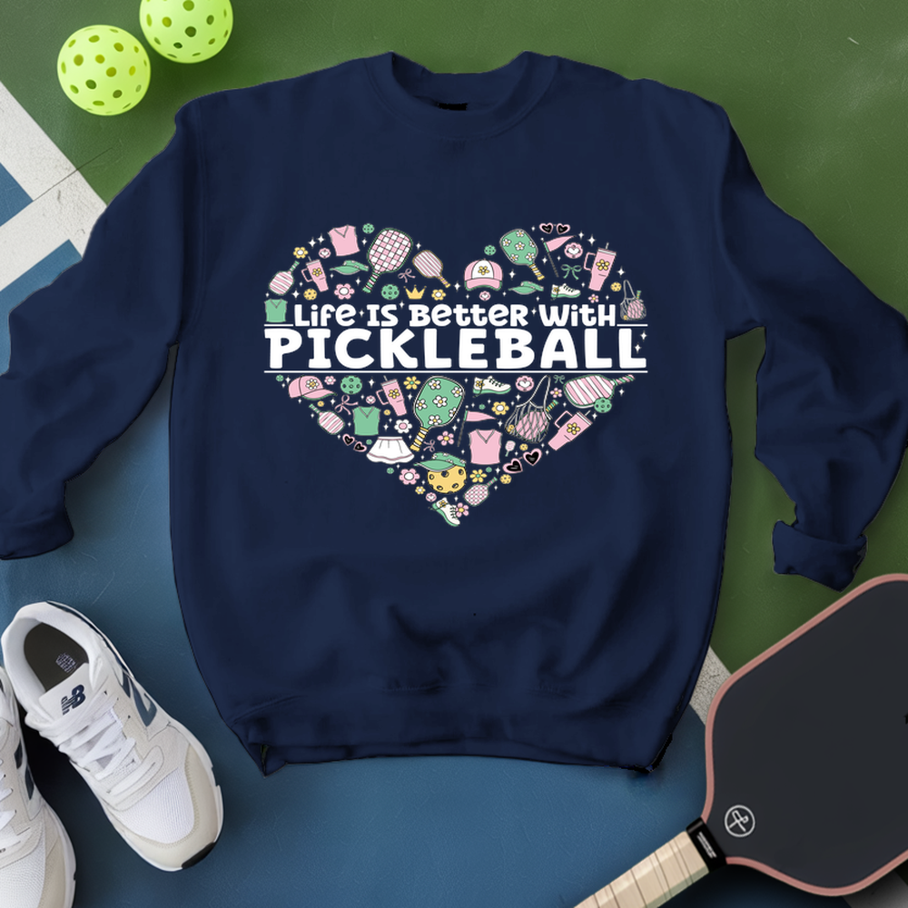 Navy blue sweatshirt with pickleball-themed design on a green and blue surface with pickleballs and a paddle.
