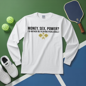 White long-sleeve shirt with pickleball-themed text and graphics on a green and blue surface with pickleball equipment.