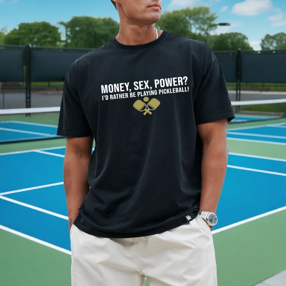 Person wearing a black t-shirt with pickleball-themed text on a tennis court