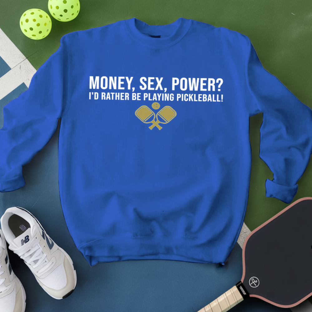 Blue sweatshirt with pickleball-themed text and graphics on a green surface with pickleballs and a paddle.
