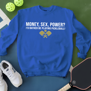 Blue sweatshirt with pickleball-themed text and graphics on a green surface with pickleballs and a paddle.