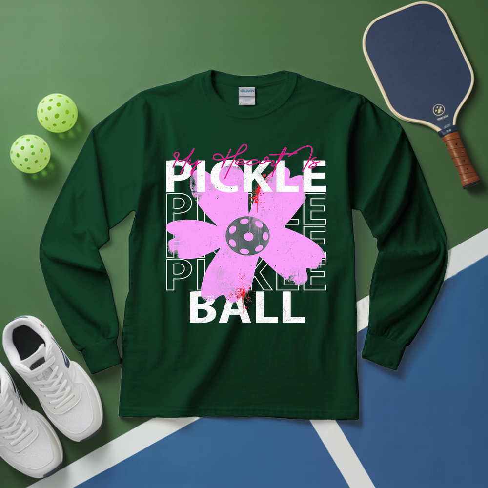 Green long-sleeve shirt with pickleball design on a green and blue surface with pickleball equipment.