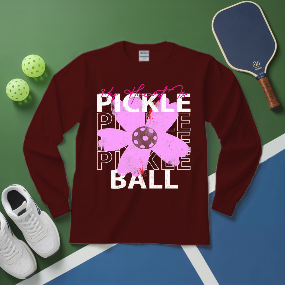Maroon long-sleeve shirt with pickleball design on a green and blue surface with pickleball equipment.