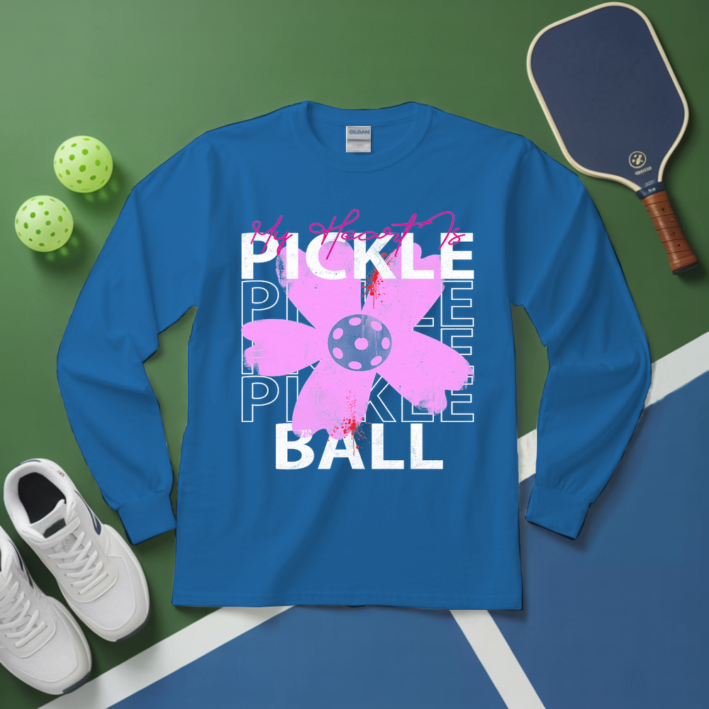 Blue long-sleeve shirt with pickleball design on a green and blue background with pickleball equipment.
