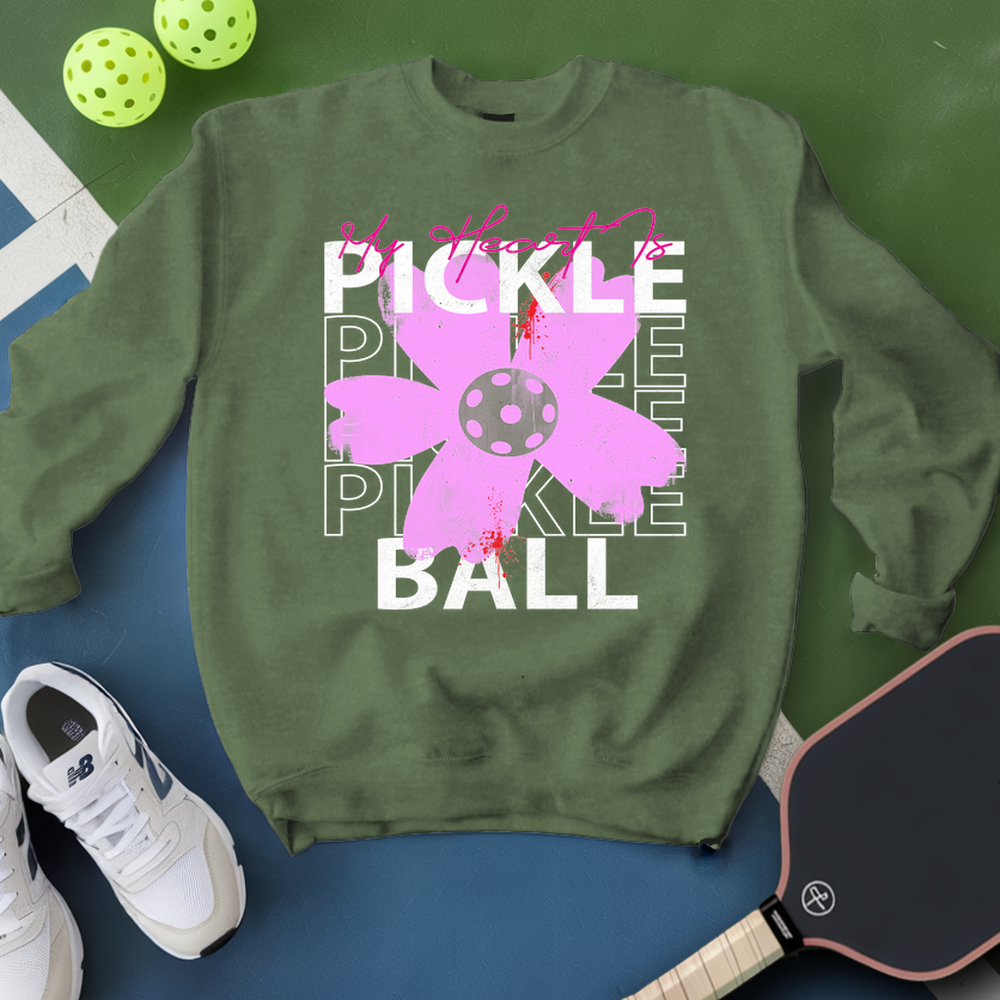 Green sweatshirt with pickleball-themed design on a green and blue background with pickleballs and a paddle.