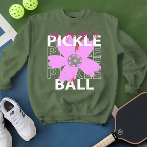 Green sweatshirt with pickleball-themed design on a green and blue background with pickleballs and a paddle.