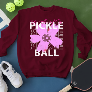 Maroon sweatshirt with pickleball design on a green and blue background