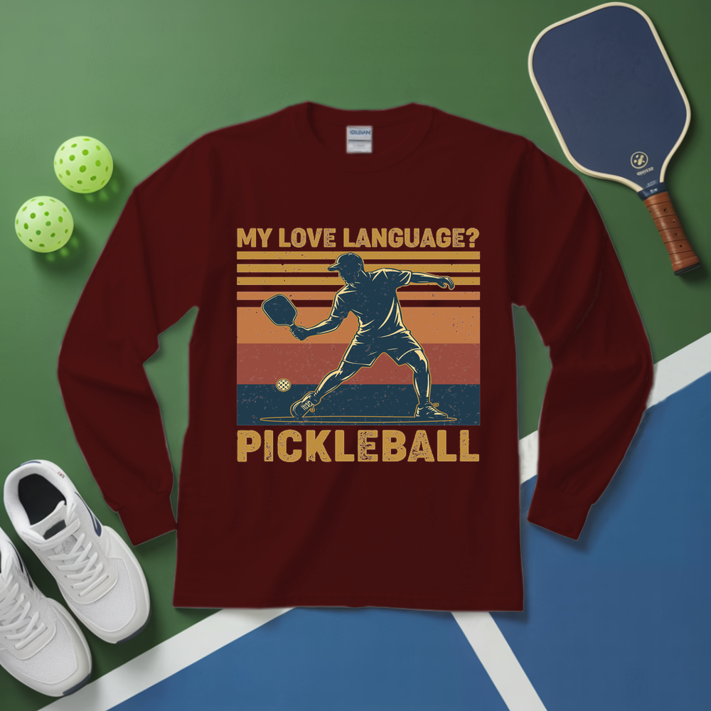 Maroon long-sleeve shirt with pickleball design on a green and blue surface with pickleball equipment.