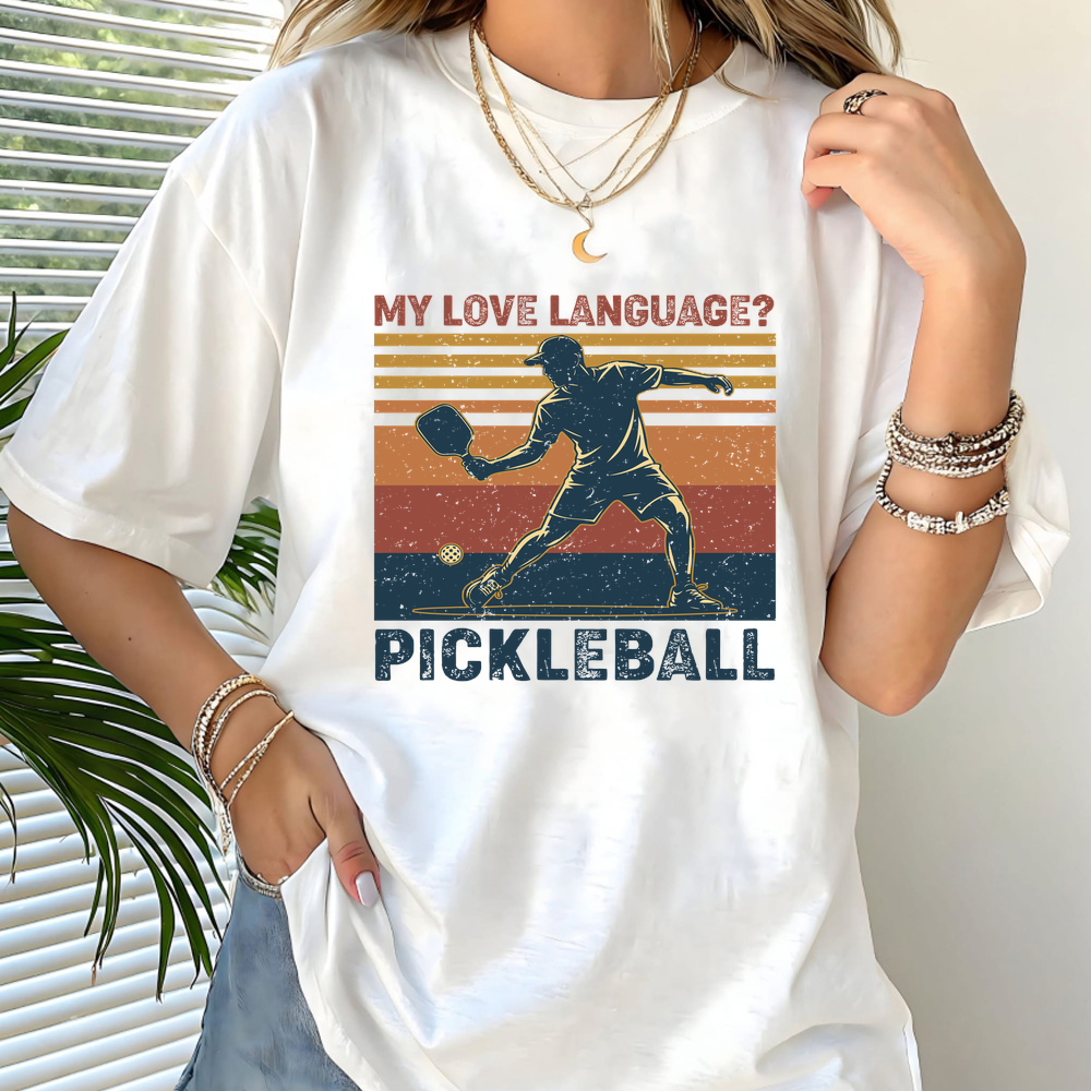 Person wearing a white t-shirt with pickleball design and text.