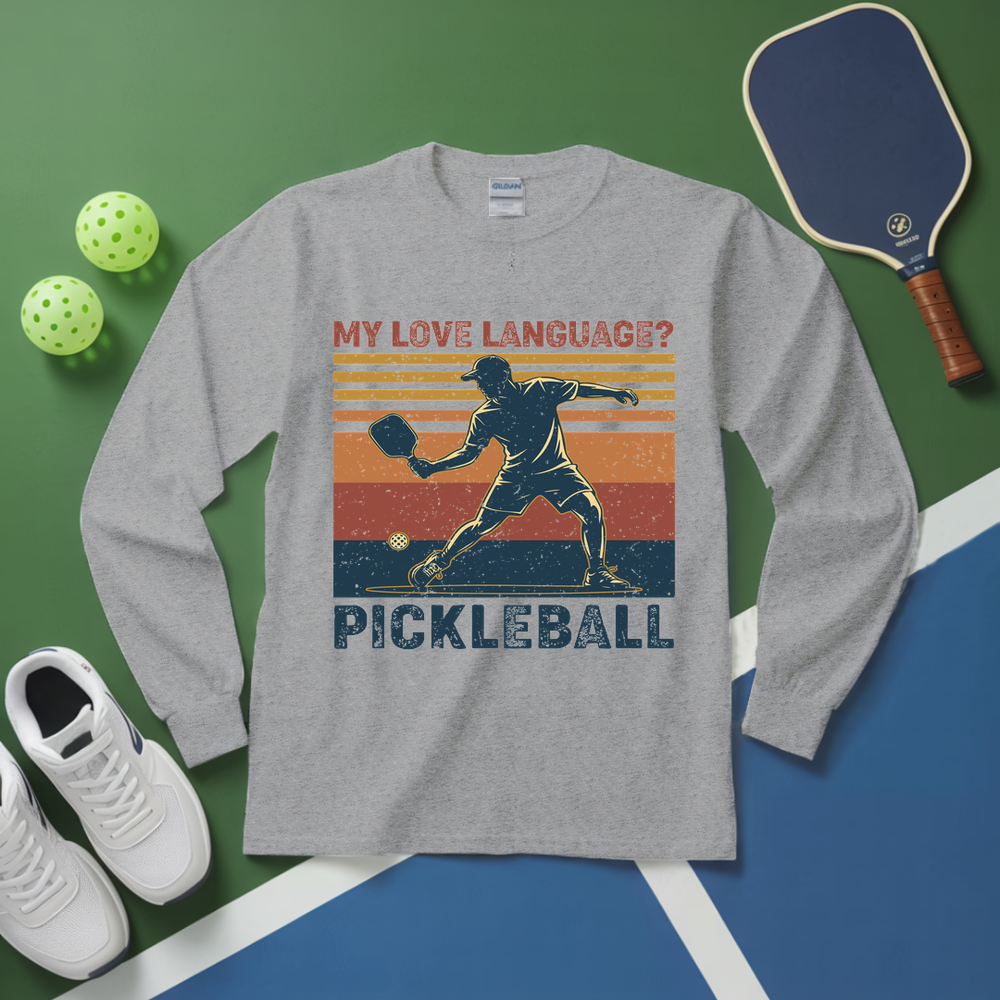 Gray long-sleeve shirt with pickleball design on a green and blue background with pickleball equipment.