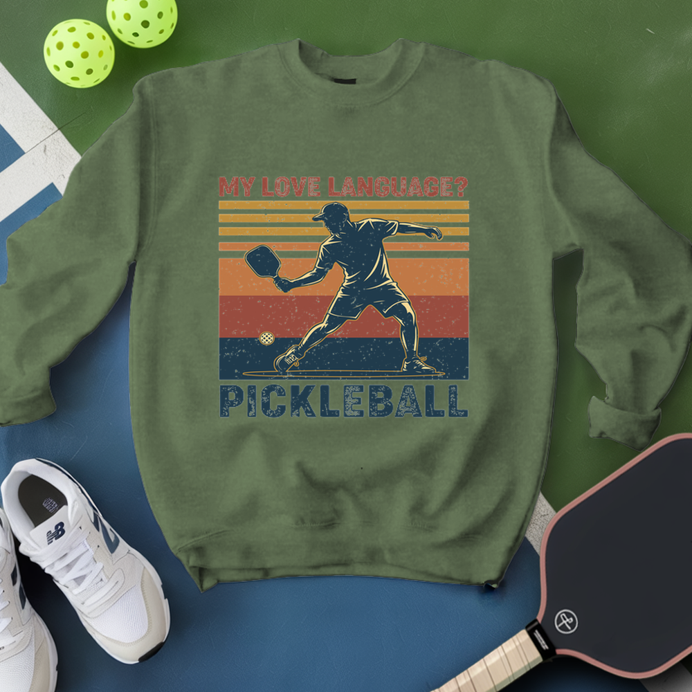 Green sweatshirt with pickleball design and accessories on a green and blue background