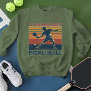 Green sweatshirt with pickleball design and accessories on a green and blue background