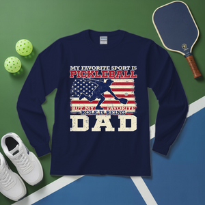 Navy blue sweatshirt with pickleball design and text on a green and blue background with pickleball equipment.