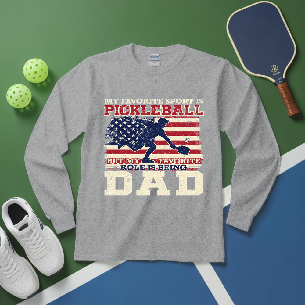 Gray long-sleeve shirt with pickleball-themed design on a green and blue surface with pickleball equipment.
