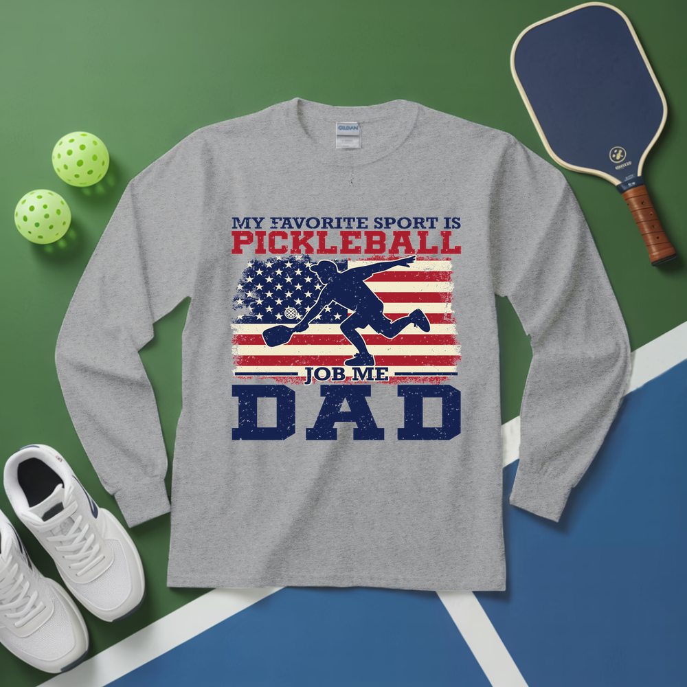 Gray long-sleeve shirt with pickleball-themed design on a green and blue surface with pickleball equipment.