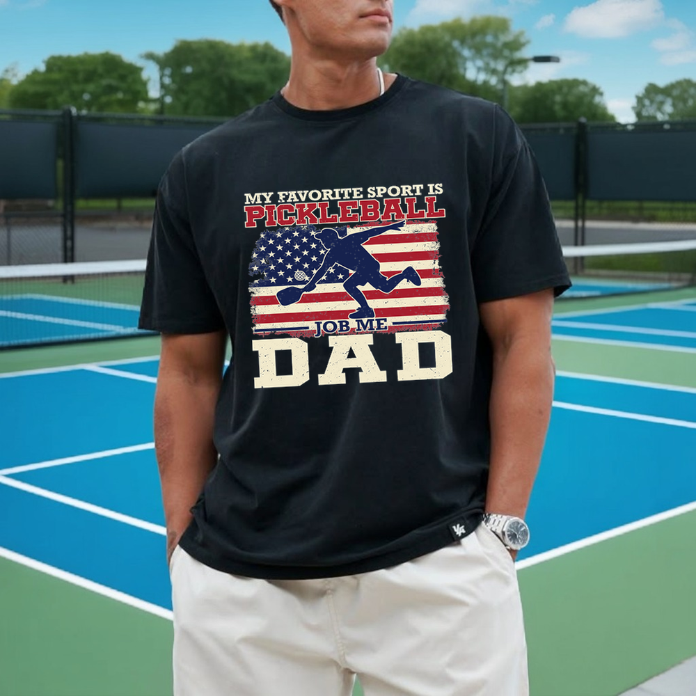 Person wearing a black t-shirt with pickleball-themed design on a tennis court