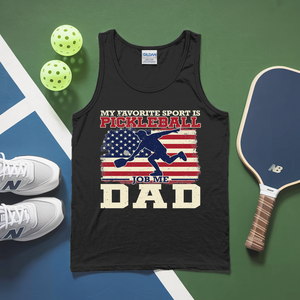 Black tank top with pickleball-themed design on a green and blue surface with pickleballs and a paddle.