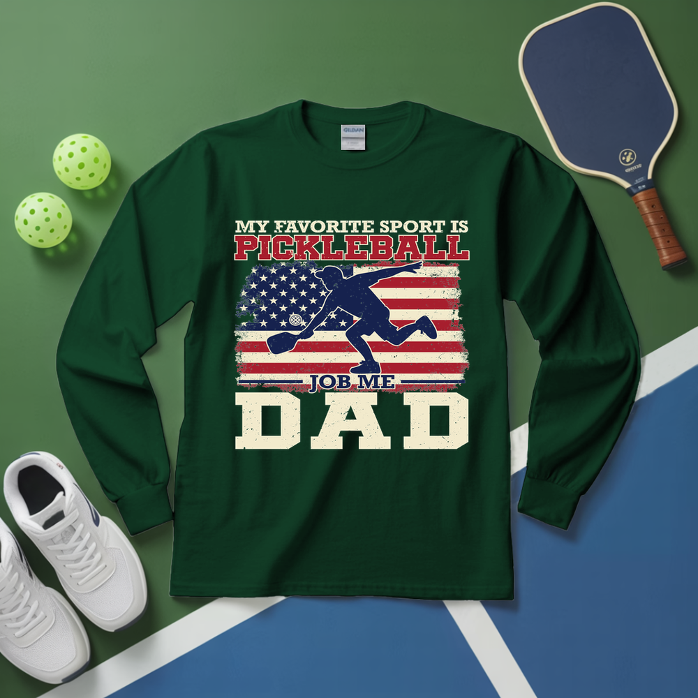 Green long-sleeve shirt with pickleball-themed design on a green and blue surface with pickleball equipment.