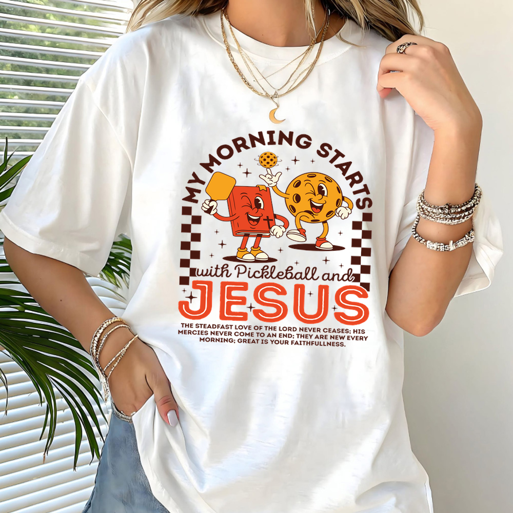 Person wearing a white t-shirt with pickleball and Jesus graphic design.