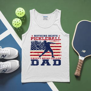 White tank top with pickleball-themed design on a green and blue surface with pickleballs and a paddle.