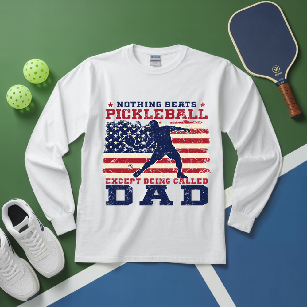 White long-sleeve shirt with pickleball-themed design on a green and blue background with pickleball equipment.