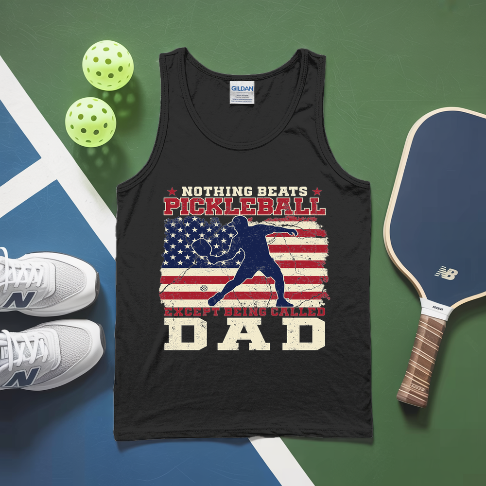 Black tank top with pickleball design and text, placed on a green and blue surface with pickleballs and a paddle.