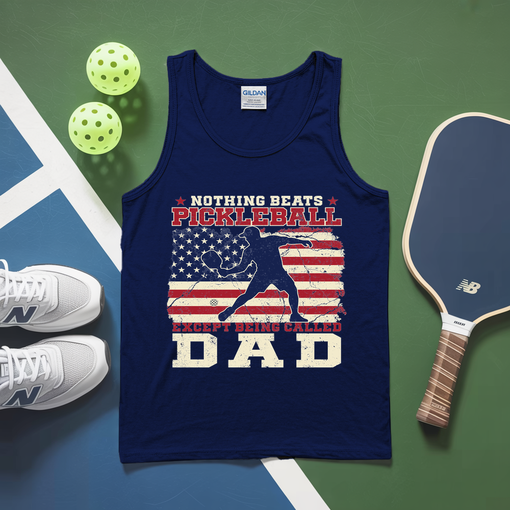 Navy tank top with pickleball design and text, placed on a green and blue surface with pickleballs and a paddle.