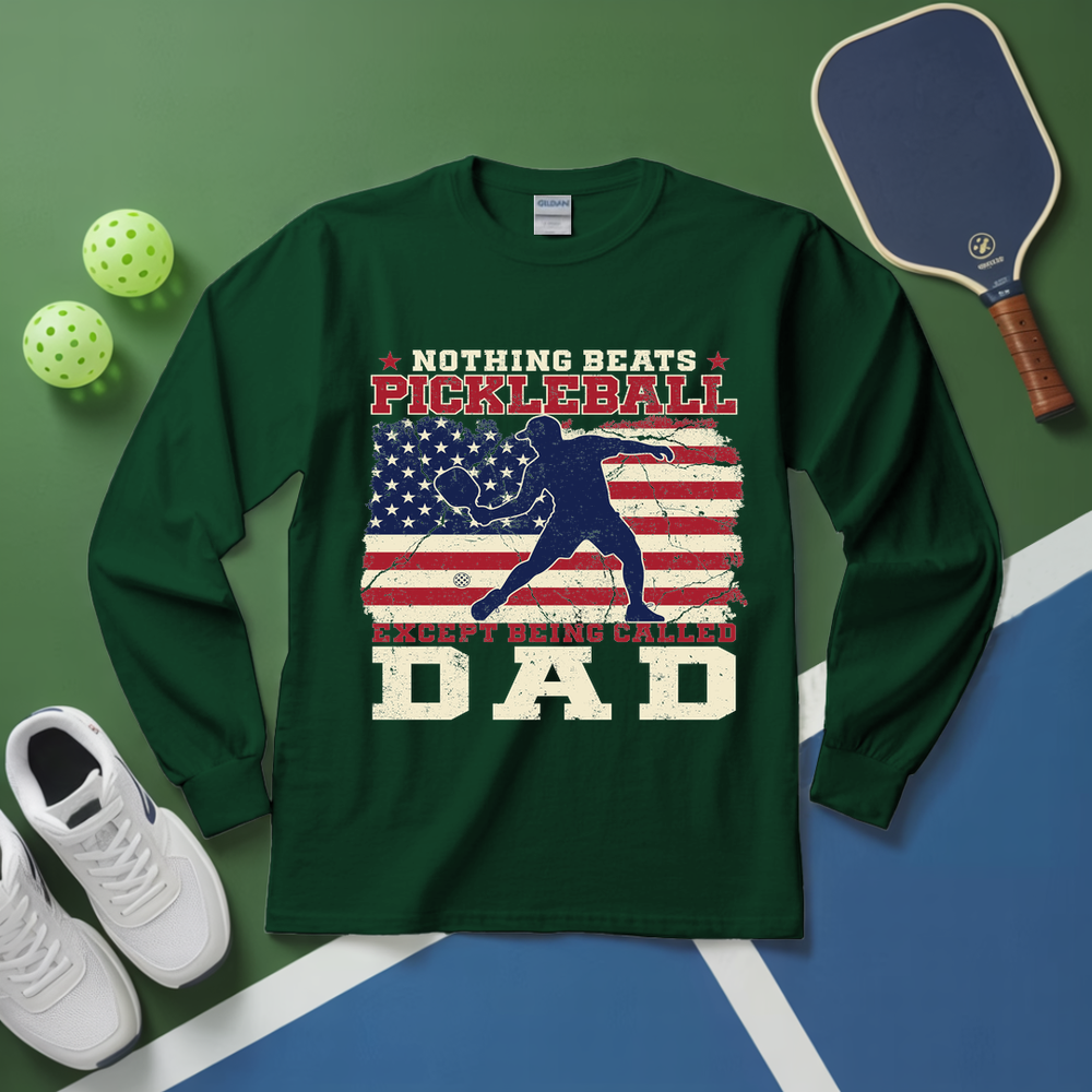Green long-sleeve shirt with pickleball design on a green and blue surface with pickleball equipment.