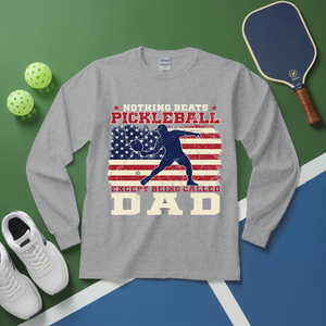 Gray long-sleeve shirt with pickleball design and accessories on a green and blue surface