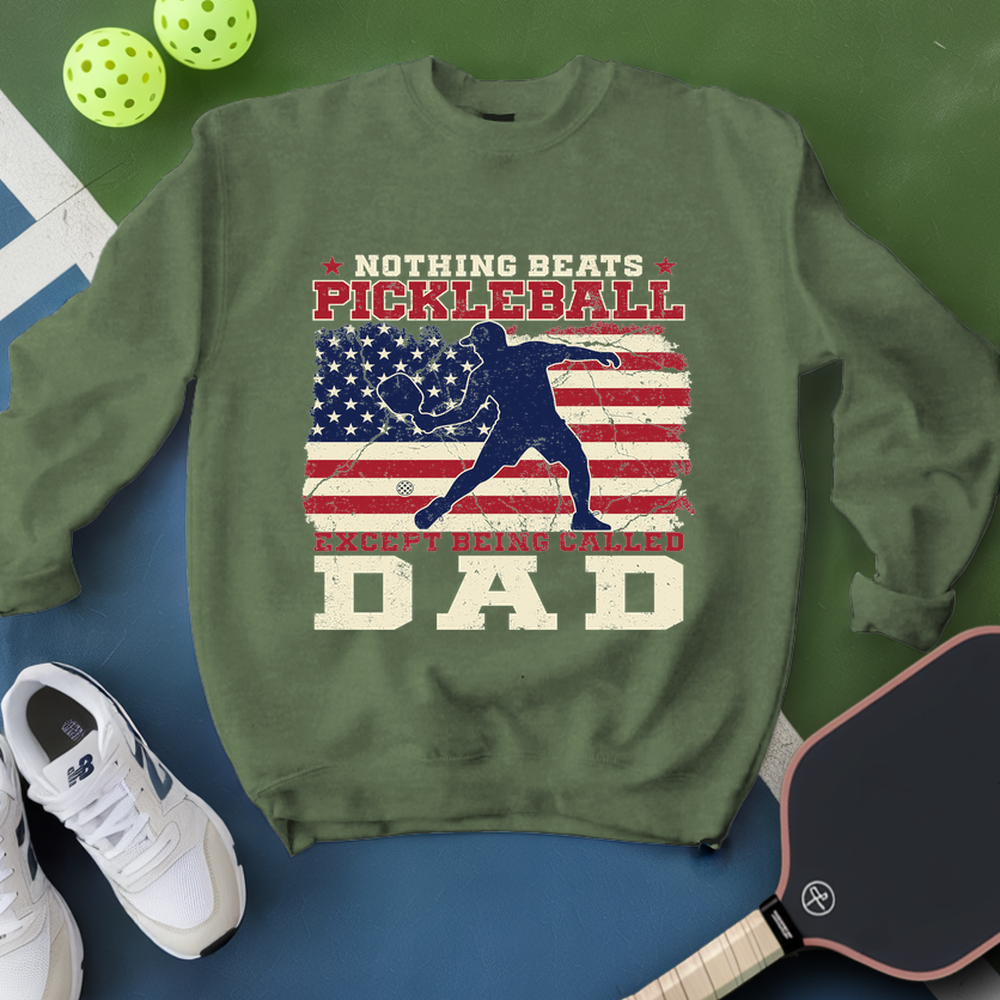 Green sweatshirt with pickleball design and text, surrounded by pickleballs and a paddle on a green and blue background.