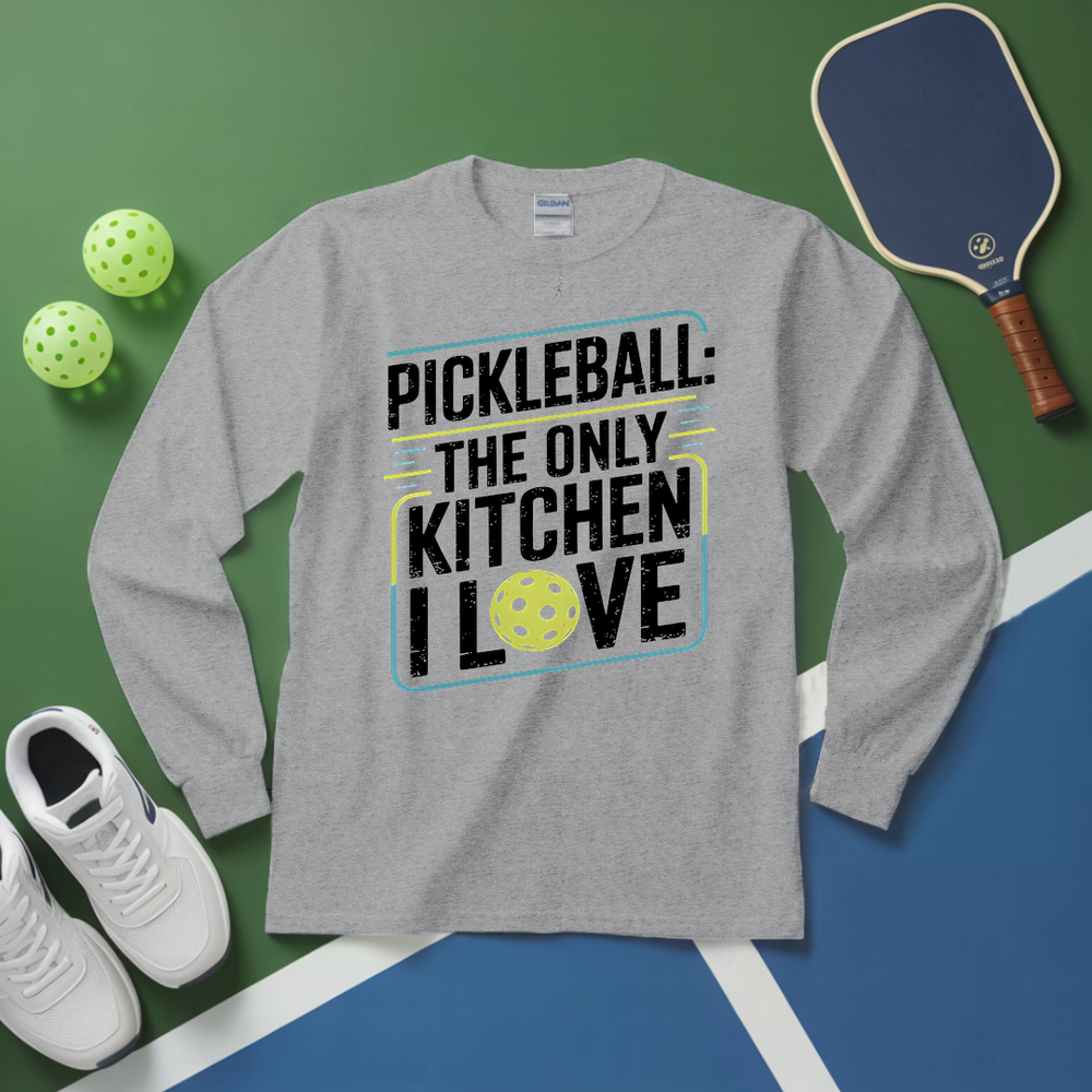Gray long-sleeve shirt with pickleball-themed text on a green and blue surface with pickleball equipment.
