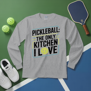 Gray long-sleeve shirt with pickleball-themed text on a green and blue surface with pickleball equipment.