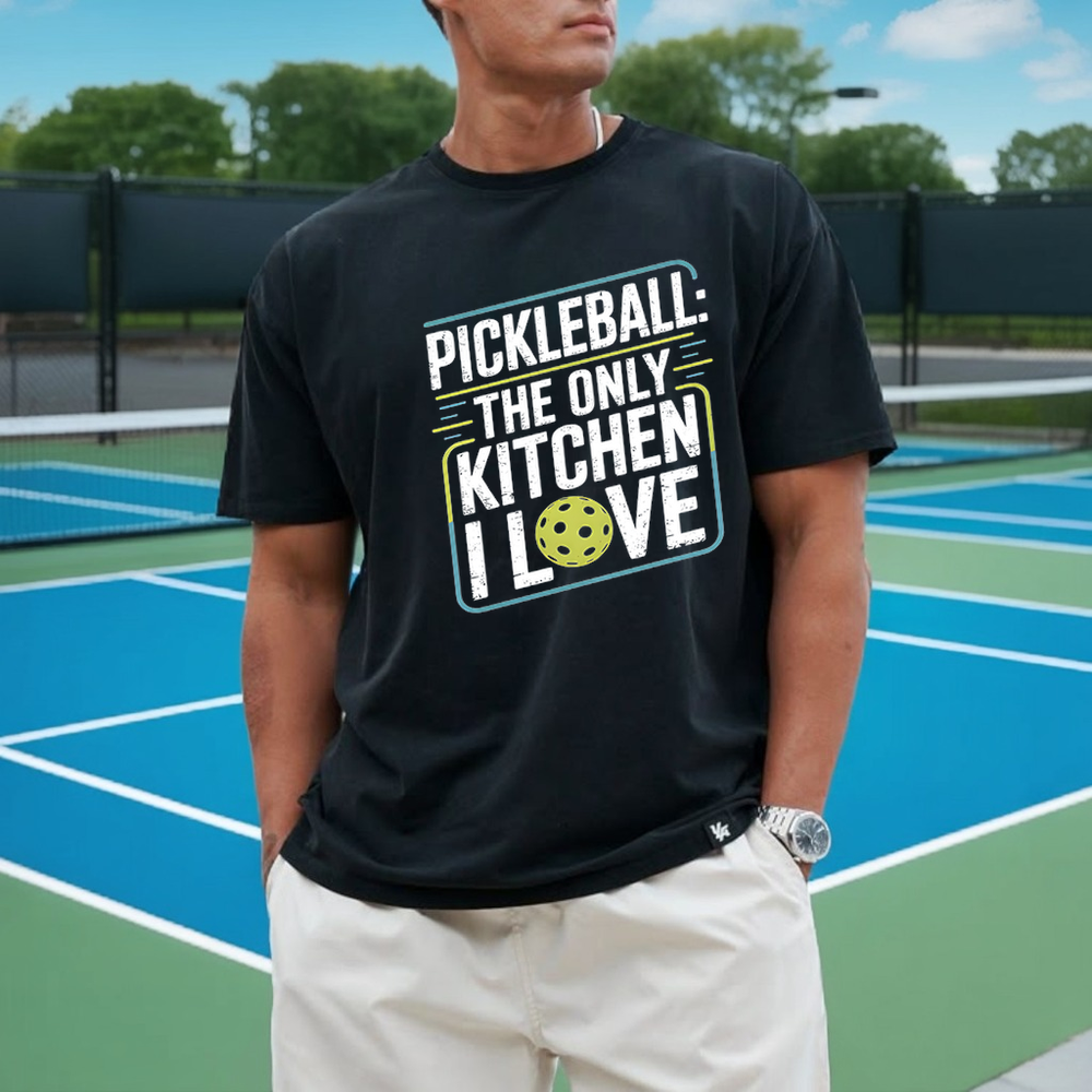 Person wearing a black t-shirt with pickleball-themed text on a tennis court