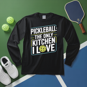 Black long-sleeve shirt with pickleball-themed text on a green and blue surface with pickleballs and a paddle.