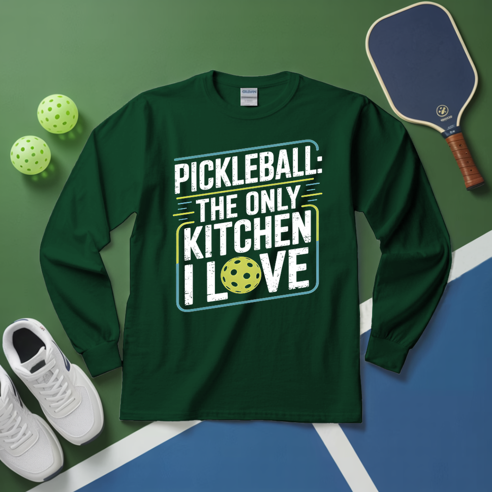 Green long-sleeve shirt with pickleball-themed text on a green and blue surface with pickleballs and a paddle.