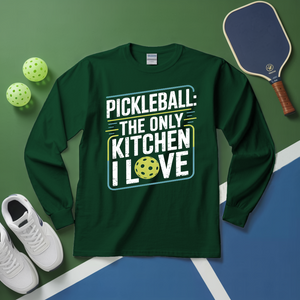 Green long-sleeve shirt with pickleball-themed text on a green and blue surface with pickleballs and a paddle.