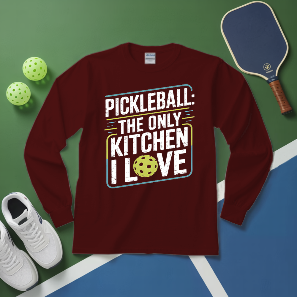 Maroon long-sleeve shirt with pickleball-themed design on a green and blue surface with pickleballs and a paddle.