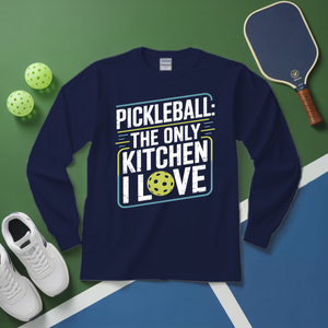 Navy blue sweatshirt with pickleball-themed text on a green and blue surface with pickleballs and a paddle.