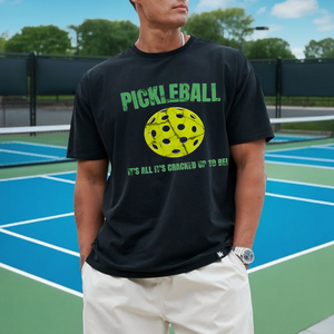 Person wearing a black t-shirt with pickleball design on a tennis court