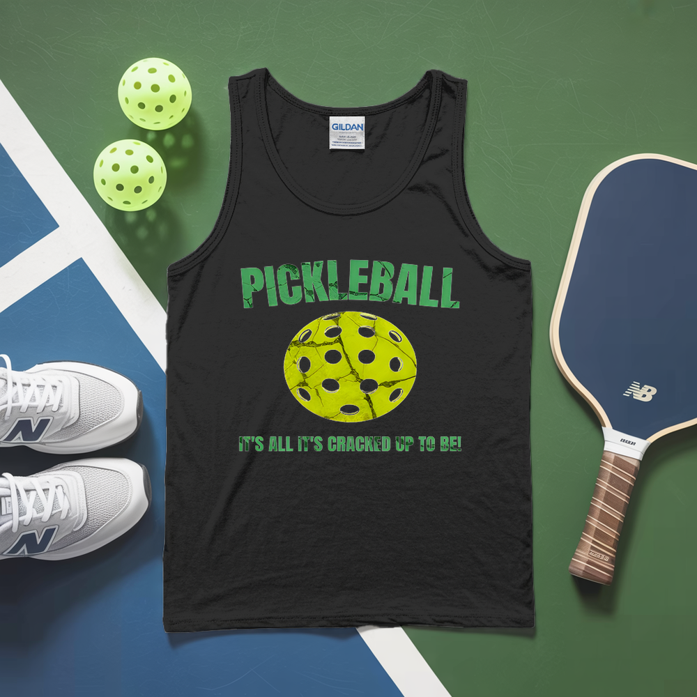 Black tank top with pickleball design and text, pickleballs, paddle, and sneakers on a green and blue surface.