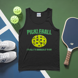 Black tank top with pickleball design and text, pickleballs, paddle, and sneakers on a green and blue surface.