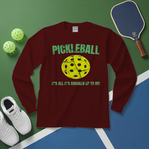 Maroon long-sleeve shirt with pickleball design on a green and blue surface with pickleballs and a paddle.